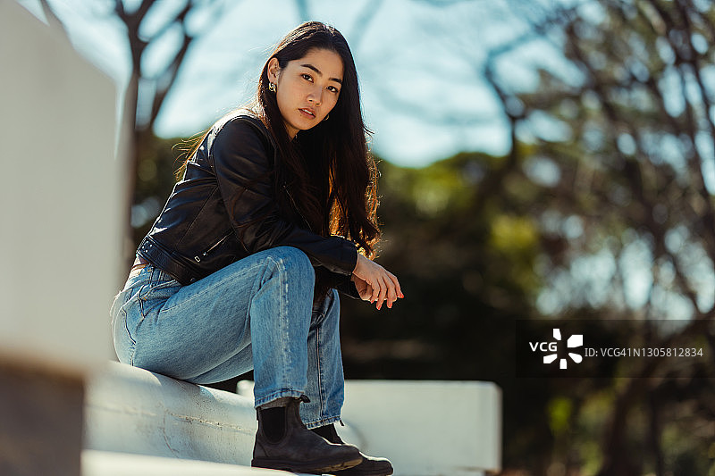 坐在公园里看着镜头的年轻漂亮酷女郎肖像图片素材