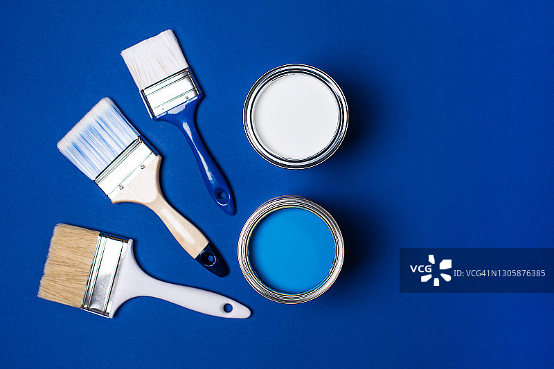 明亮蓝色背景下的油漆刷和金属桶：家居室内重新装修概念图片素材