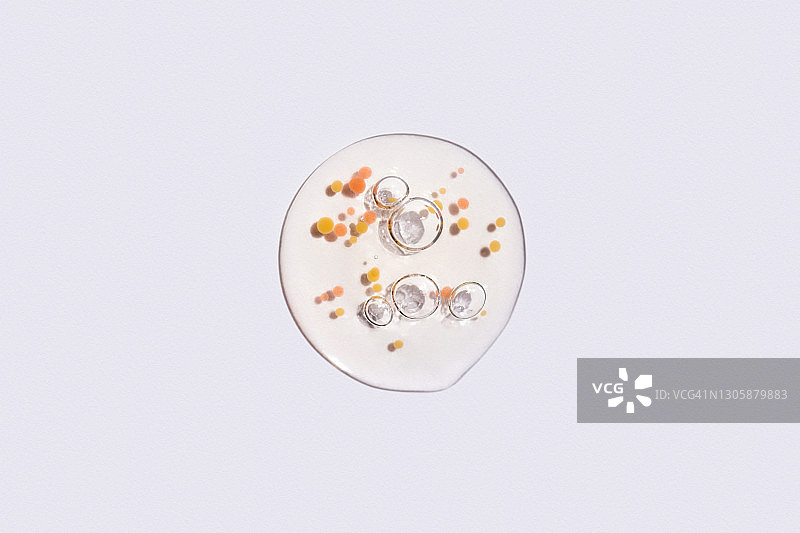 有机精油或保湿乳液滴，气泡，橙色颗粒，白色背景图片素材