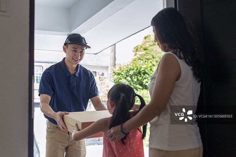 小女孩在家从送货员那里收到披萨盒图片素材