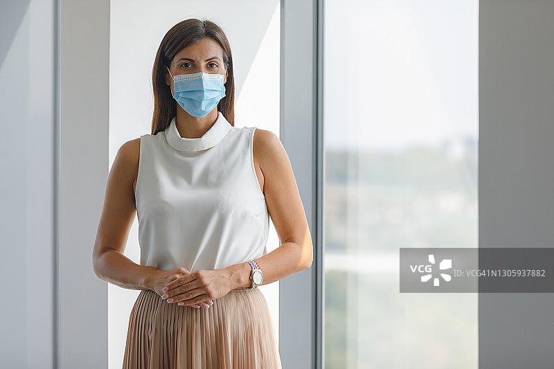 戴着防护口罩的优雅商务女人看着镜头图片素材