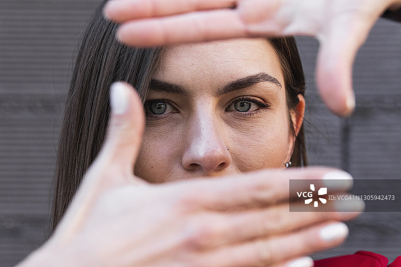 灰眼睛的女人靠墙用手指做框架图片素材