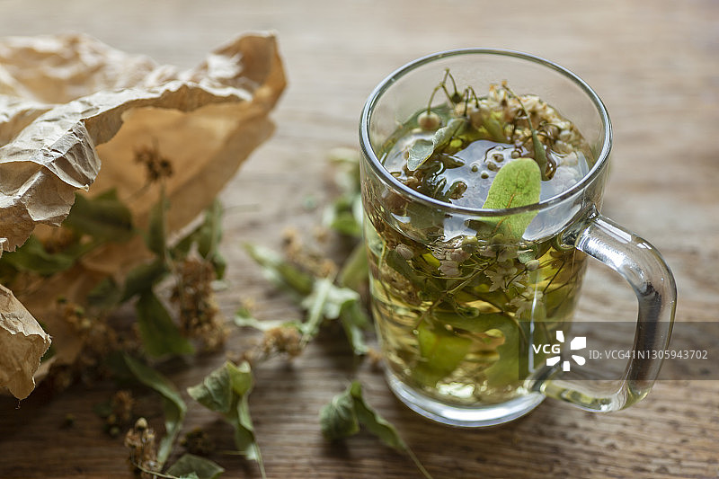 牛皮纸袋装椴树叶青柠茶，置于木制砧板上图片素材