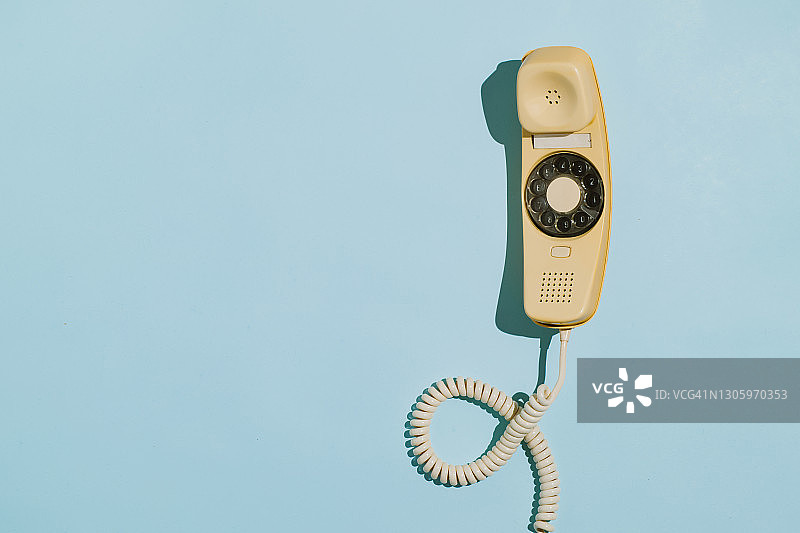 蓝色背景上黄色电话听筒的特写图片素材