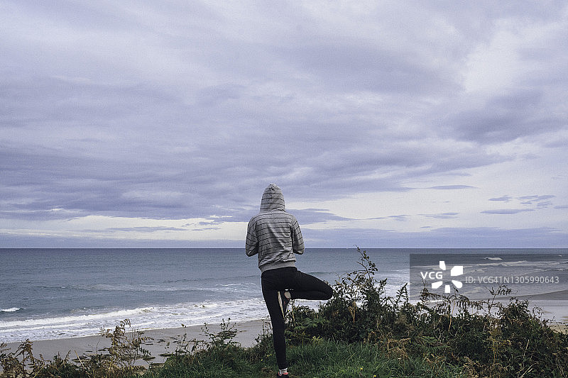 女人在悬崖上做瑜伽（树式）图片素材