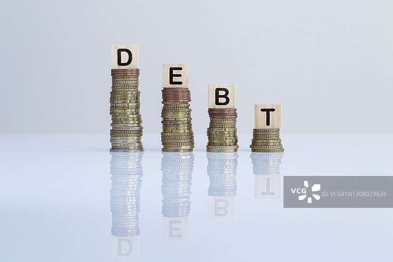 灰色背景下硬币堆上的“债务”字样图片素材