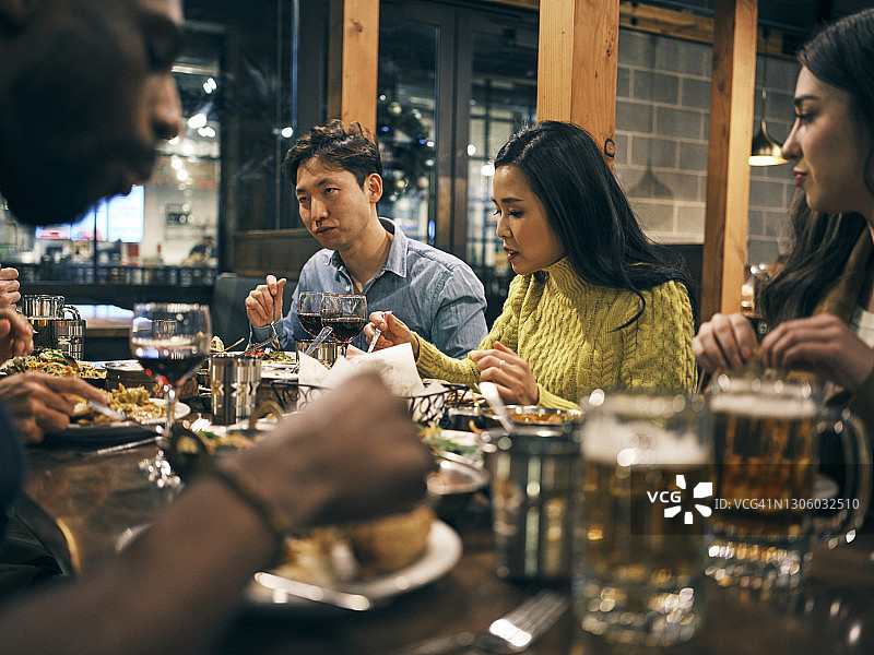 在印度餐厅里聚餐的不同种族朋友图片素材