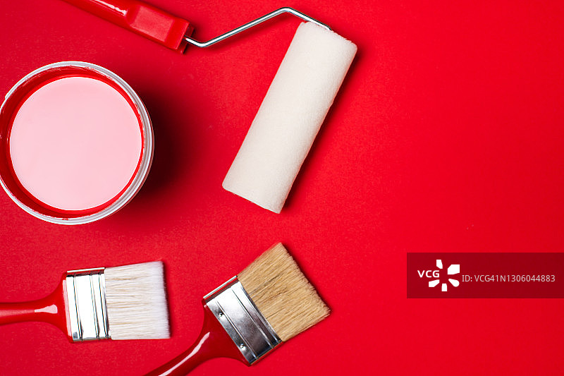 明亮红色背景上的绘画工具组合：刷子和滚筒放置在液态红色油漆桶附近。扁平风格。为您的设计复制空间。家庭室内重新装修的概念。设计理念的颜色样本图片素材