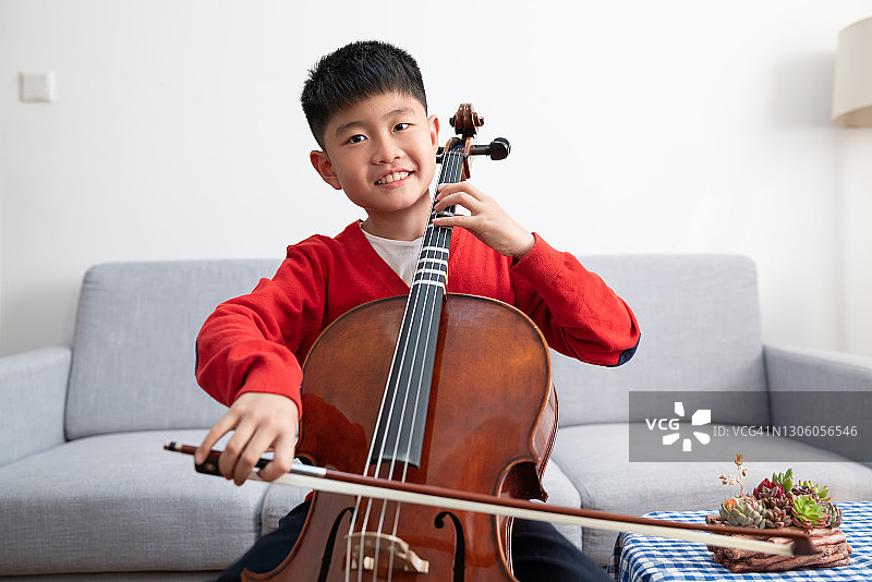 男孩在室内练习大提琴图片素材