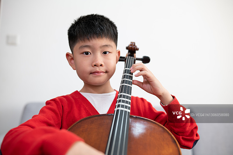 男孩在室内练习大提琴图片素材