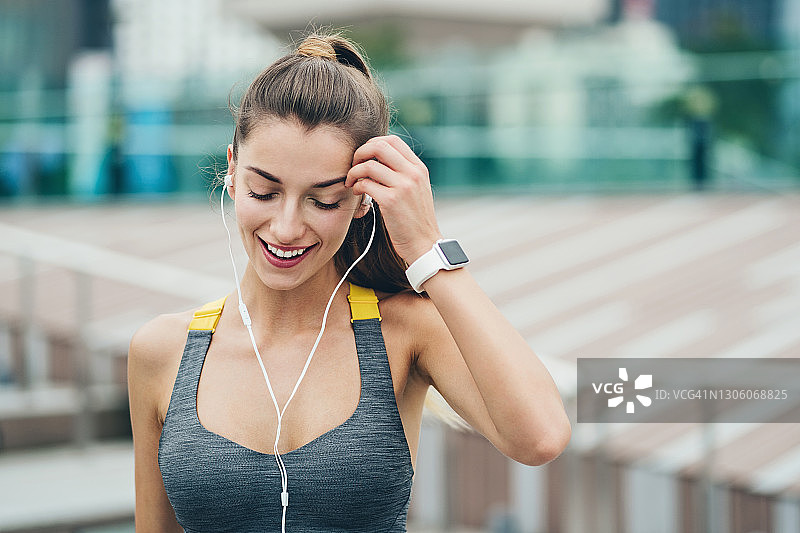 佩戴智能手表的微笑年轻女运动员图片素材