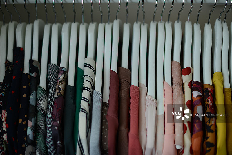 一排白色衣架上悬挂的各种颜色的衬衫（按颜色排列）图片素材