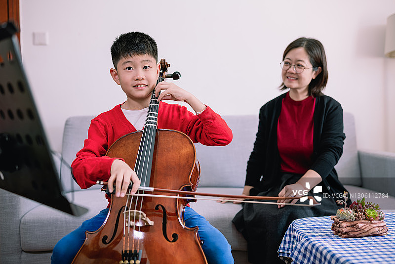 小男孩在家和老师一起练习大提琴图片素材