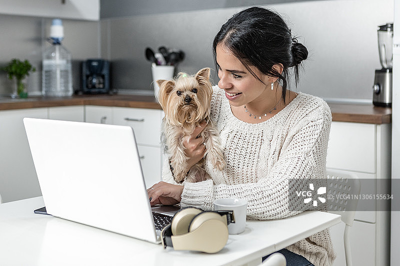 快乐的女人在网上工作时拥抱狗图片素材