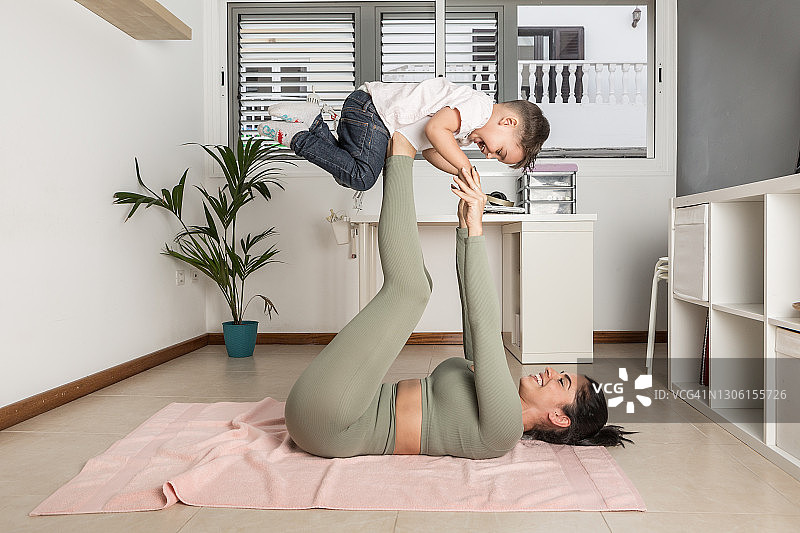 快乐的母亲在家和孩子一起玩耍和做瑜伽图片素材