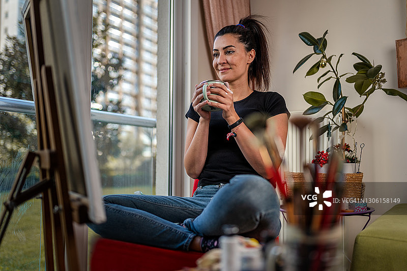 千禧一代女艺术家在公寓里绘画的肖像图片素材