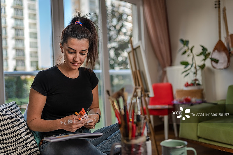 千禧一代女艺术家在公寓里绘画的肖像图片素材