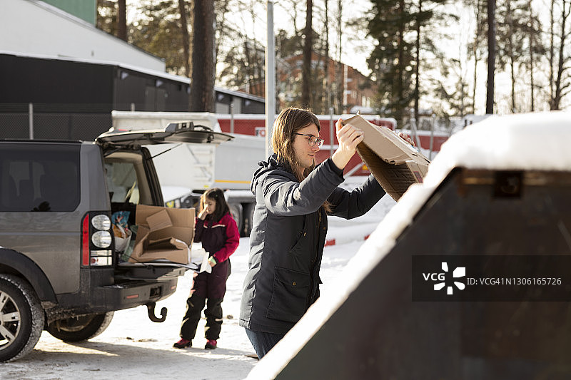 年轻人将纸板箱放入回收箱图片素材