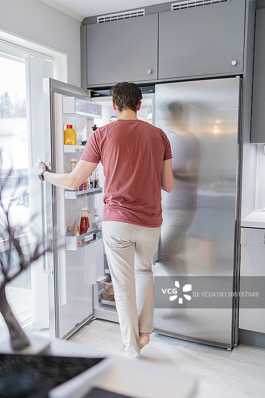 男人站在打开的冰箱前图片素材