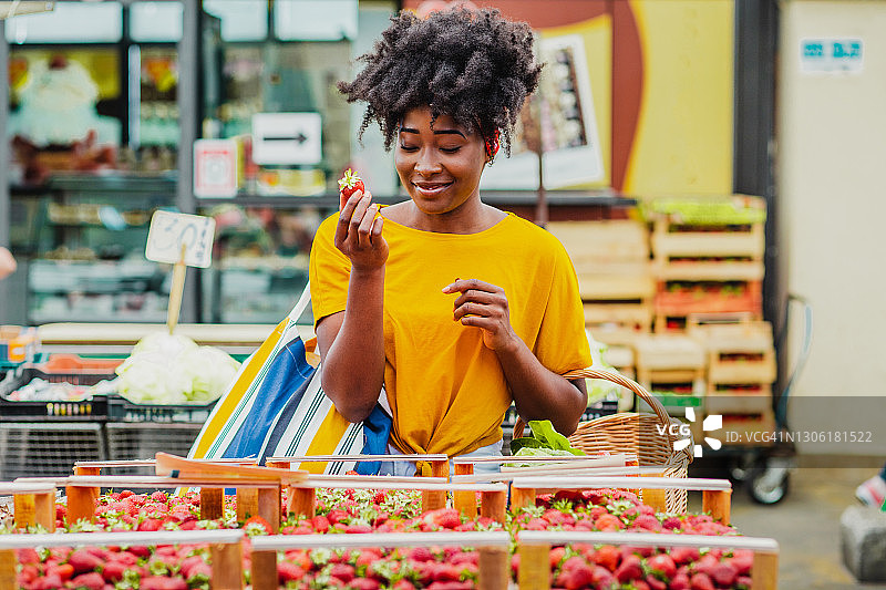 年轻的非洲女人在市场上购买水果图片素材