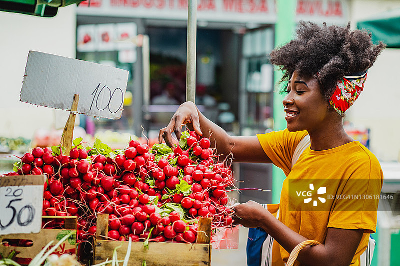 年轻的非洲女人在市场上购买蔬菜图片素材