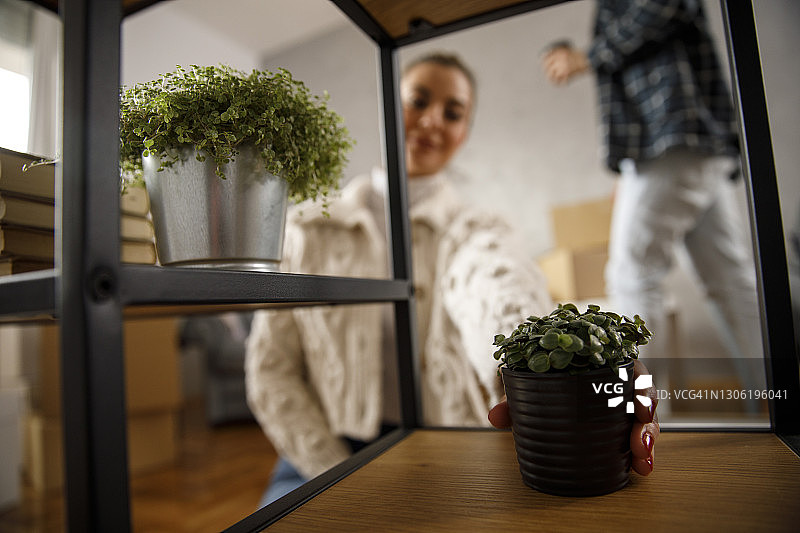 年轻女人在新公寓的架子上摆放盆栽图片素材