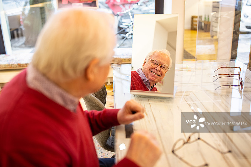 在眼镜店试戴新眼镜的年长男人图片素材
