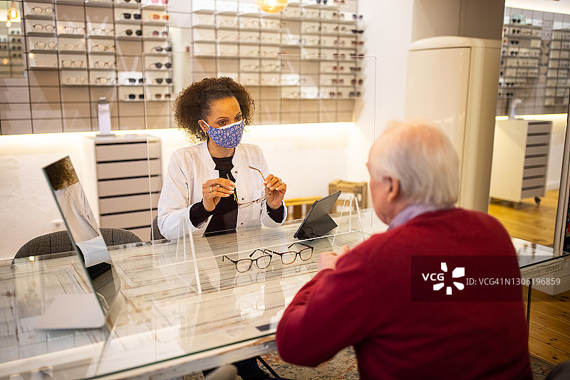 戴口罩的眼科医生帮助老年顾客图片素材