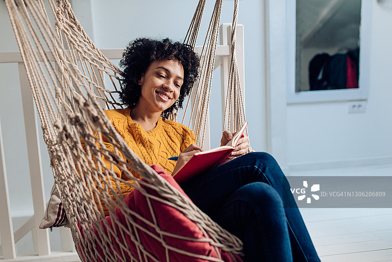 在吊床上享受并撰写商业计划的漂亮非裔美国女人图片素材