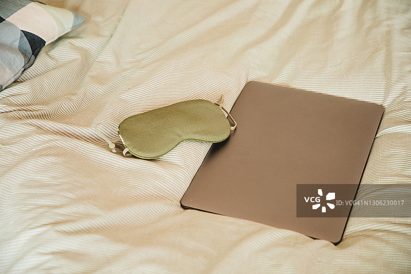 床上笔记本电脑和睡眠眼罩图片素材