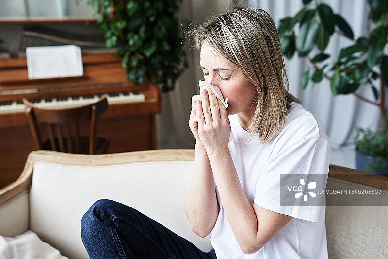 坐在客厅沙发上擤鼻涕的女孩图片素材