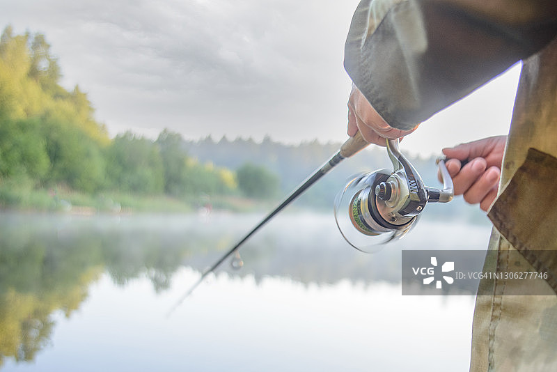 男人在水库里用钓竿钓鱼图片素材