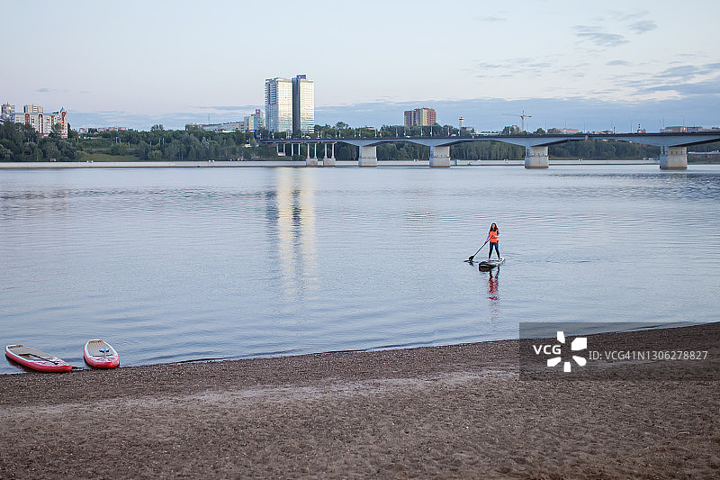 年轻女人在河里用冲浪板游泳照片图片素材
