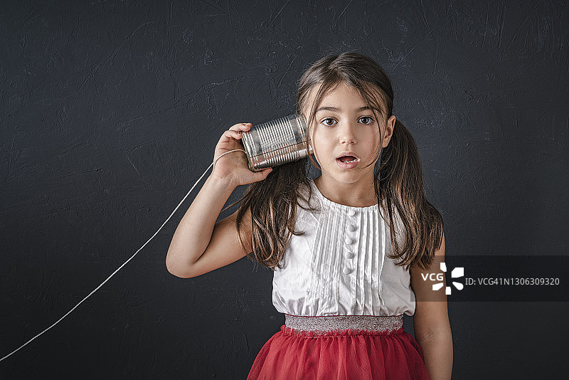 用罐头盒电话收听好奇的好消息图片素材