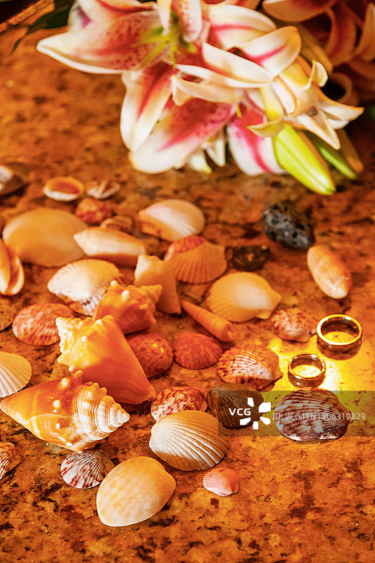 花岗岩台面上，贝壳和新娘捧花环绕的结婚戒指图片素材