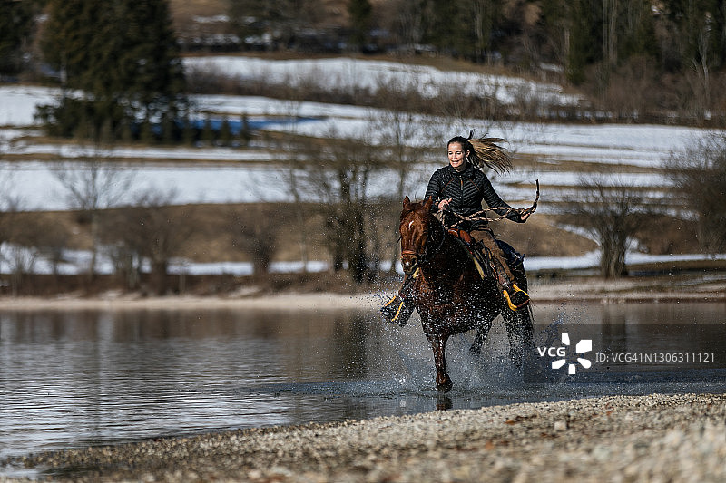 女人骑马穿过溪流图片素材