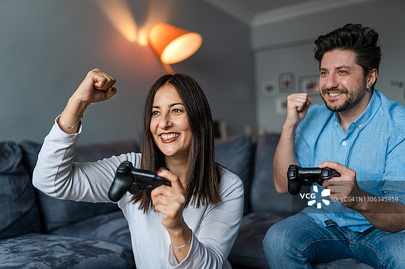 在客厅玩电子游戏的兴奋朋友们图片素材