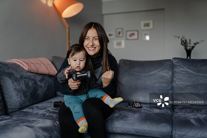 兴奋的母亲和儿子在客厅里玩电子游戏图片素材