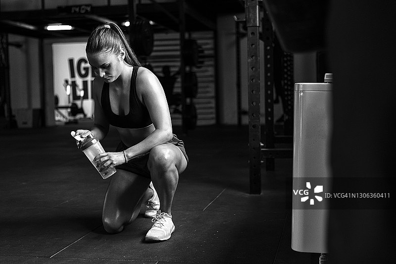 年轻女子在健身房喝水休息图片素材