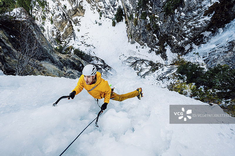 俯视攀登壮观冰冻瀑布的男性攀冰者图片素材