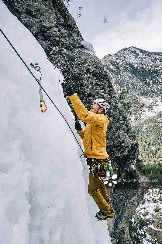 侧视图：攀冰者用两把冰镐悬挂在离地面100米的冰上图片素材