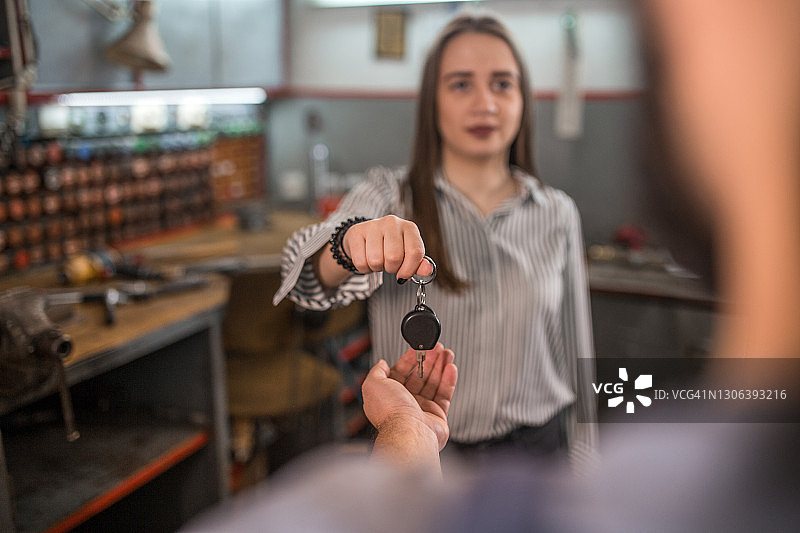 女顾客将车钥匙交给技工图片素材