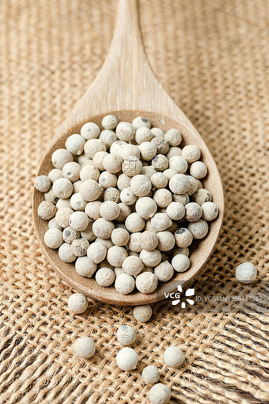 粗麻布背景木勺中的干制有机白胡椒粒图片素材