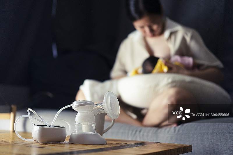选择性聚焦：亚洲新手妈妈在家用吸奶器给新生女儿喂奶图片素材