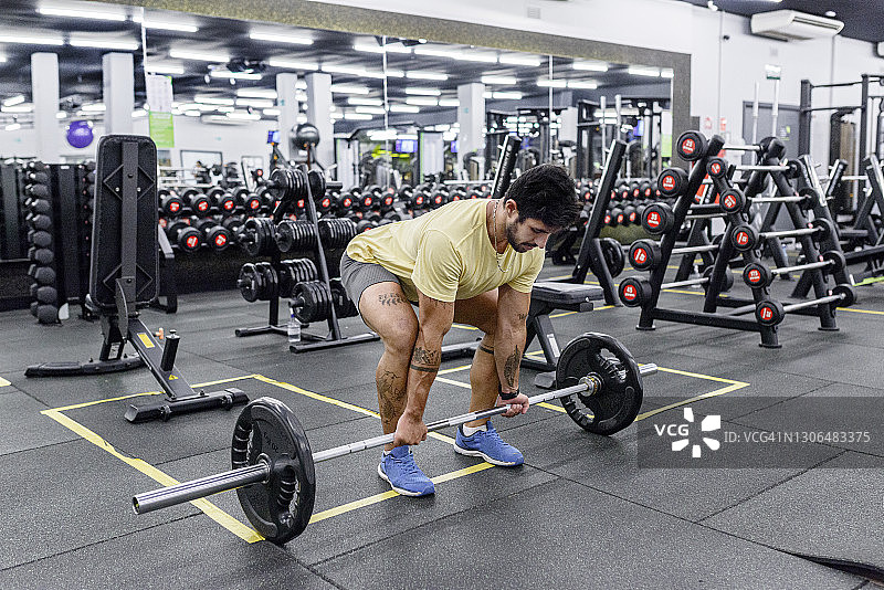 在健身房用杠铃准备硬拉的拉丁裔男人图片素材
