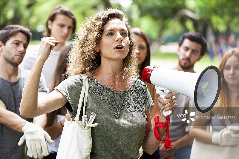 年轻女志愿者在垃圾清理活动中发表演讲图片素材