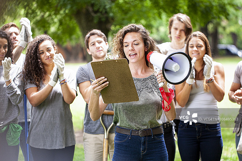 垃圾清理活动中拿着扩音器和书写板的年轻女活动家图片素材