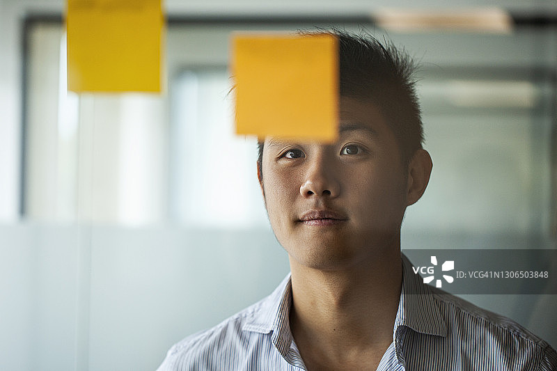 商务人士看着玻璃墙上的便签图片素材