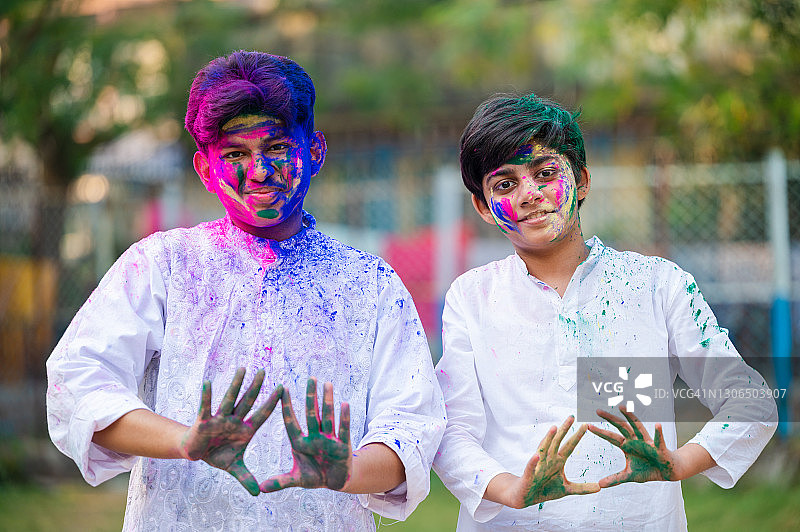 在洒红节庆祝活动中，快乐的年轻男孩们展示涂满洒红节颜料的彩色双手图片素材