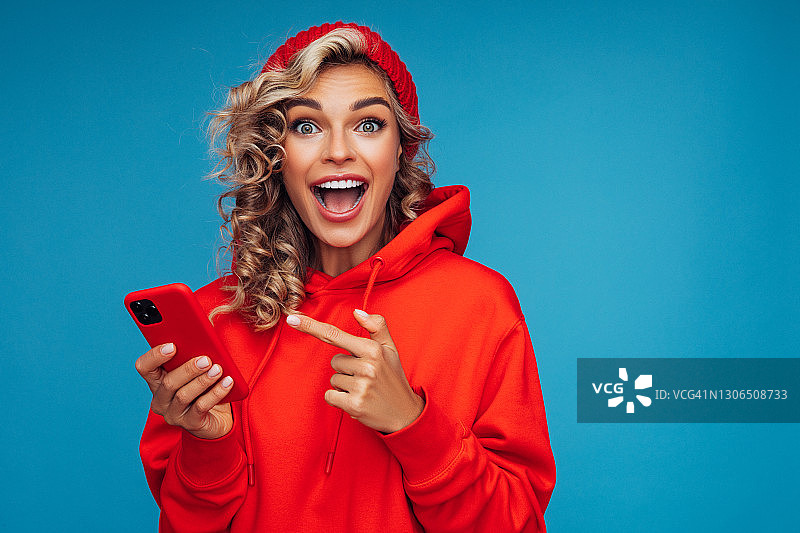 手持智能手机的漂亮女人，蓝色背景图片素材